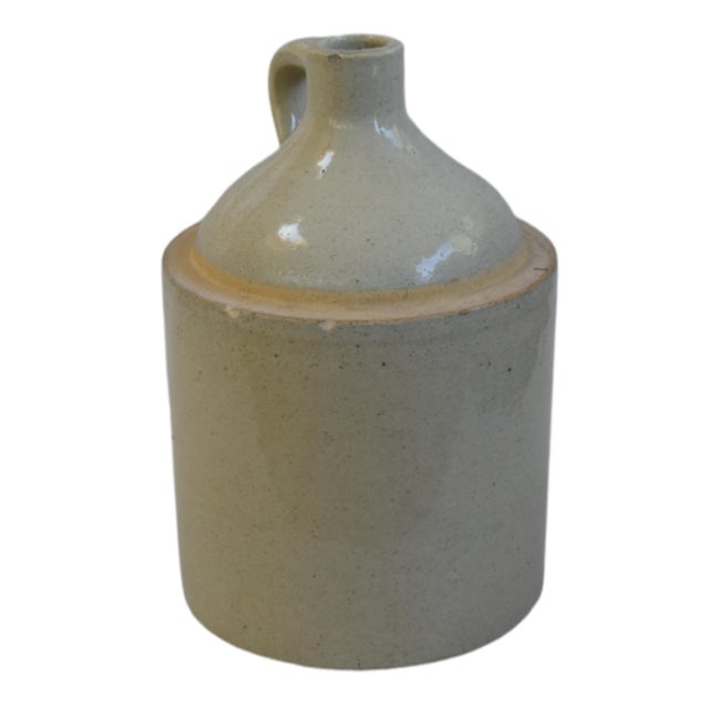 Beautifully balanced antique stoneware jug with a primitive design, featuring a rich, cream-colored cylindrical body....
