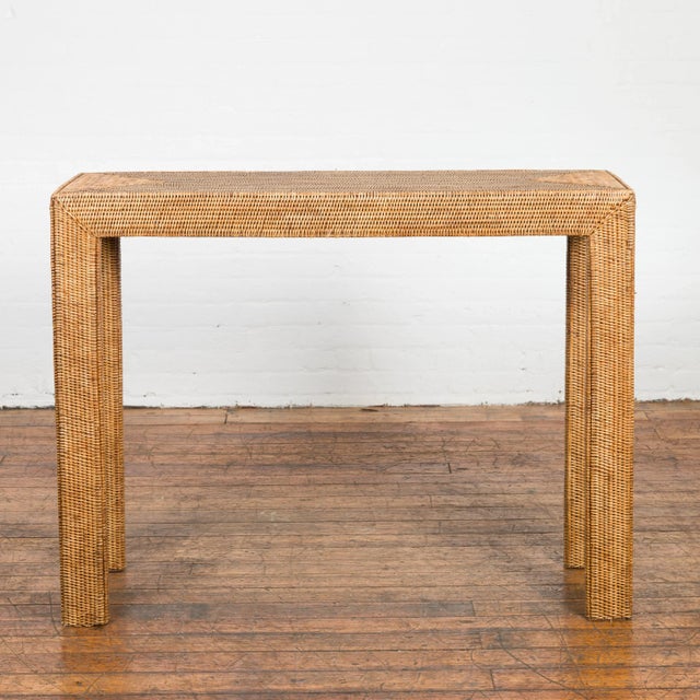 A Burmese Country style woven rattan console table from the Mid-20th Century, with straight legs and triangular patterns....