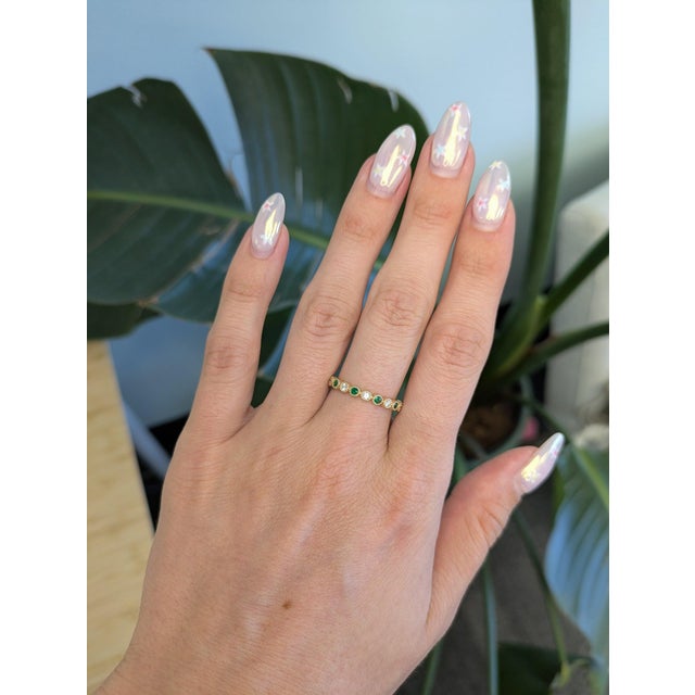 A petite Zambian emerald adds a whisper of vivid green to this delicate band, accented with tiny brilliant diamonds in...
