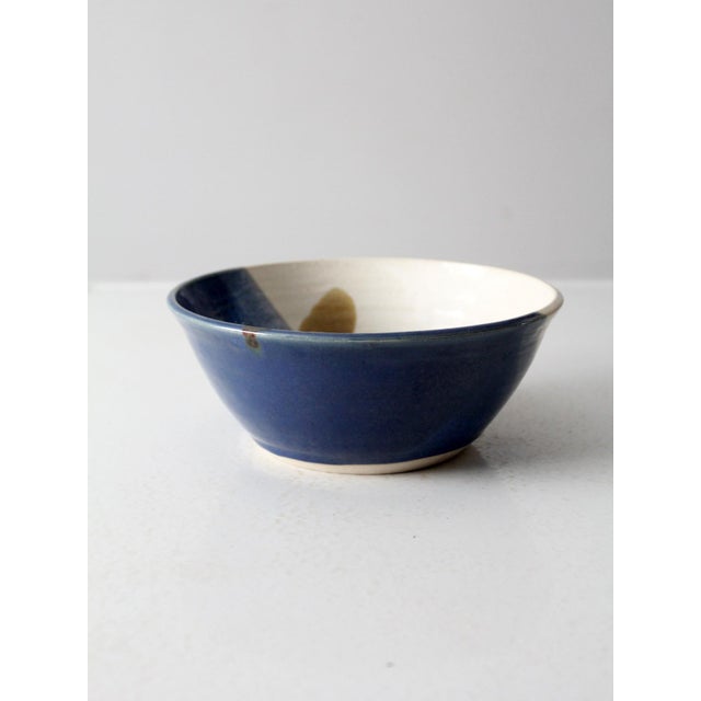 This is a vintage studio pottery bowl. Signed by the artist, the handmade bowl has a beautiful blue, cream and brown glaze.
