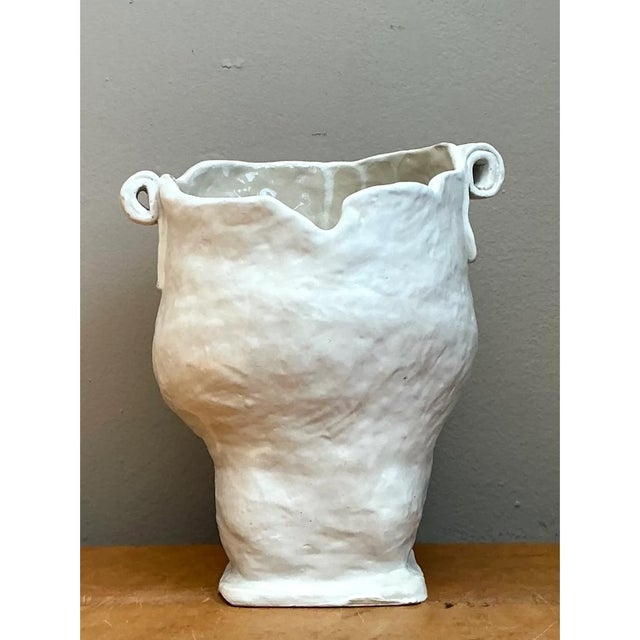 Exemplifying an organic and sculptural aesthetic, this vintage handcrafted ceramic vase features a consistent white glaze...