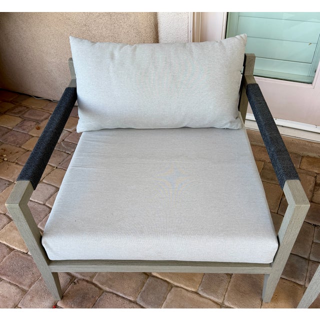 A beautiful set of two Four Hands outdoor accent chairs upholstered in stone gray performance fabric. These chairs feature...