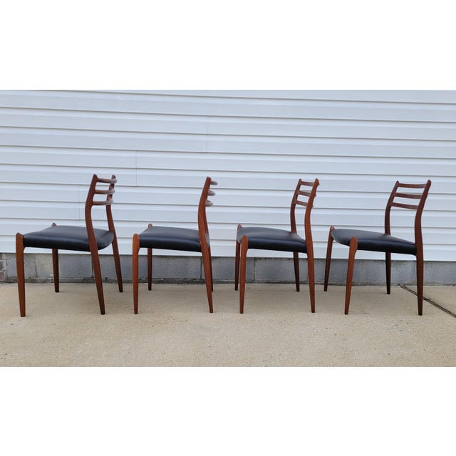 Georgeous set of four J.L. Moller teak dining chairs model 78 cira 1960's, newly reupholsted in supple black leather with...