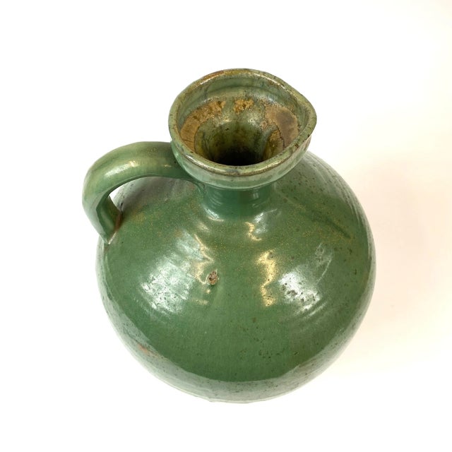 This large ceramic jug is from the 19th century and glazed with a deep green color with yellow spots. You’ll notice areas...
