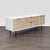 This West Elm entertainment center features a clean, modern design with a white frame and textured wood finished doors and...