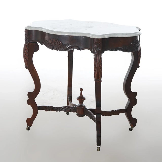 An antique Victorian parlor table offers shaped and beveled marble turtle top over rosewood base having floral accents and...