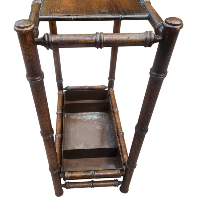 Vintage faux bamboo umbrella and cane stand featuring a warm brown walnut finish, bamboo-form frame, upper divider, and...