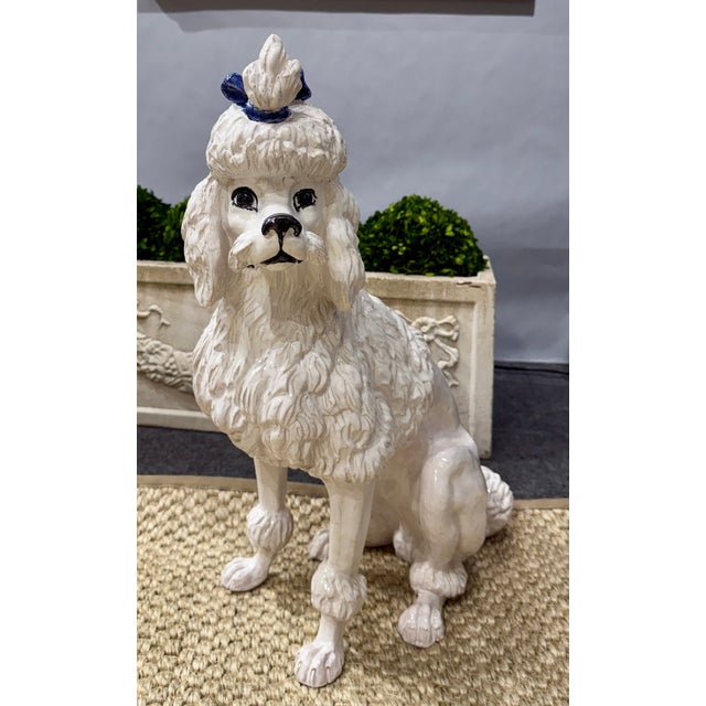 A charming Italian faience poodle figure, standing 21 ¾ inches tall and modeled in a seated pose with expressive, alert...