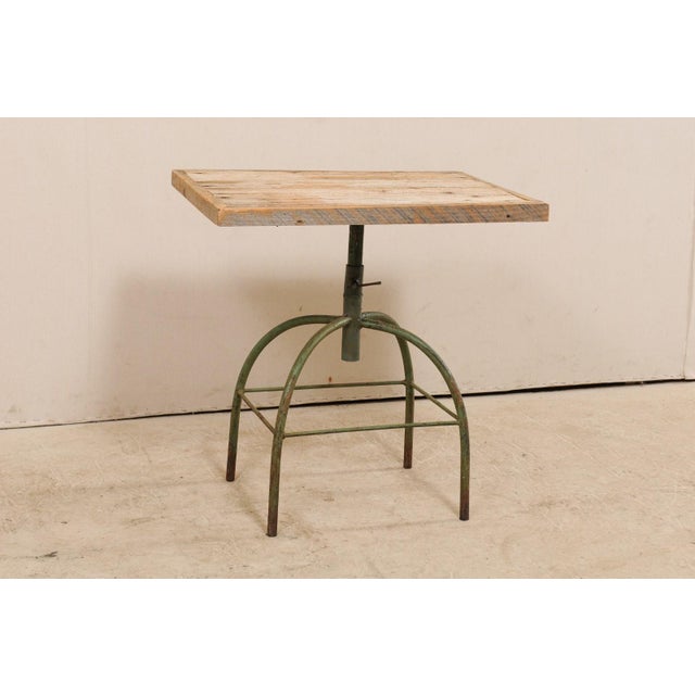 An industrial style side table with wood top over iron base. This vintage occasional table features a rectangular-shaped...