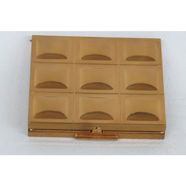 This darling powder compact is made out of gold-toned metal with a squared raised pattern on the metal lid. This vintage...