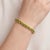 An eye-catching tennis bracelet featuring a continuous row of vibrant lime-green oval peridots set in warm gold-tone...