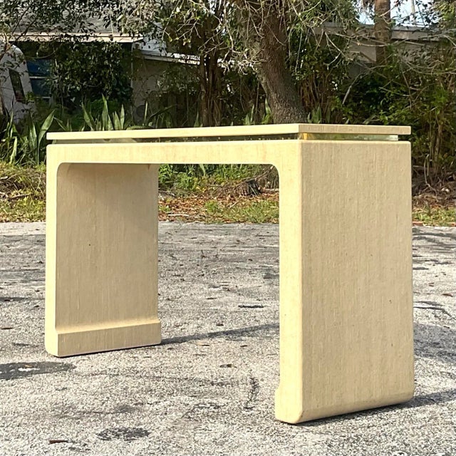A fantastic vintage Boho console table. A chic wrapped Grasscloth table with a floating top and a brass band below the...