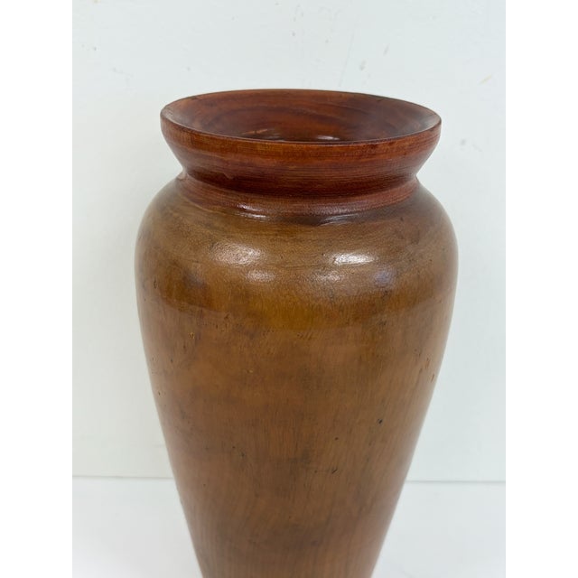 Hand turned wooden vase with a tapered form and wide flared rim. Made from solid wood with visible grain and a warm brown...