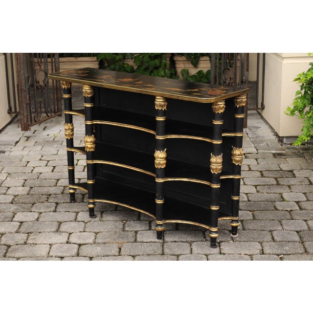 An English ebonized three-tiered freestanding shelf from the turn of the century, with chinoiserie decor and gilded...