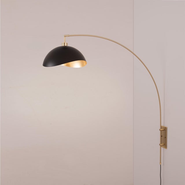 The Luna Bella Wall Arc Lamp is a striking arc lamp featuring a weathered brass steel body and a matte black and gold...