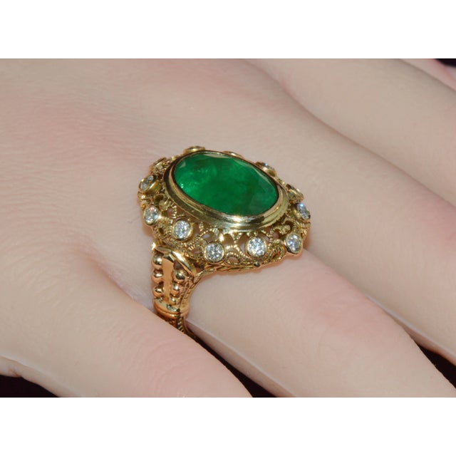 This ring features a stunning 6.64CT natural oval-cut emerald bezel set in rich solid 18K yellow gold. The center emerald...