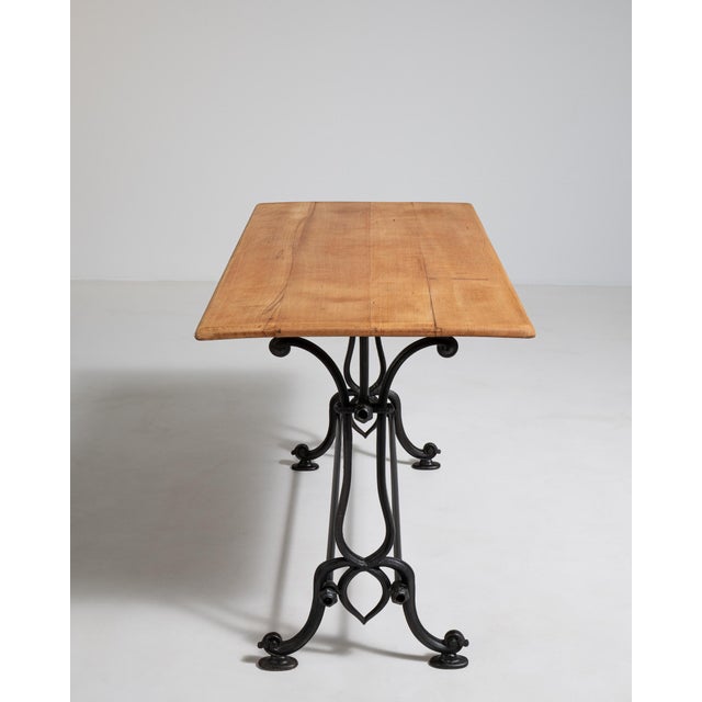 A compact French early 20th century bistro side table with a cast iron base and wooden top, designed for smaller seating...