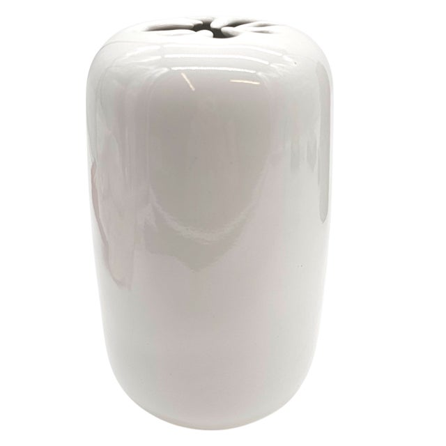 It sits upright like a whispered idea—white as pause, round as breath. The top flares with an asterisk, a spark frozen...