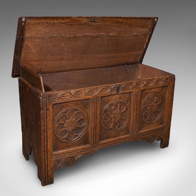 This is an antique linen chest. An English, carved oak three panel coffer or bay window seat, dating to the William III...