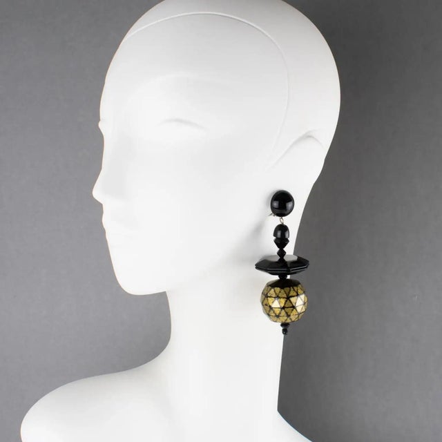 These stunning Angela Caputi, made in Italy, resin clip-on earrings feature a dangling shape with black geometric elements...