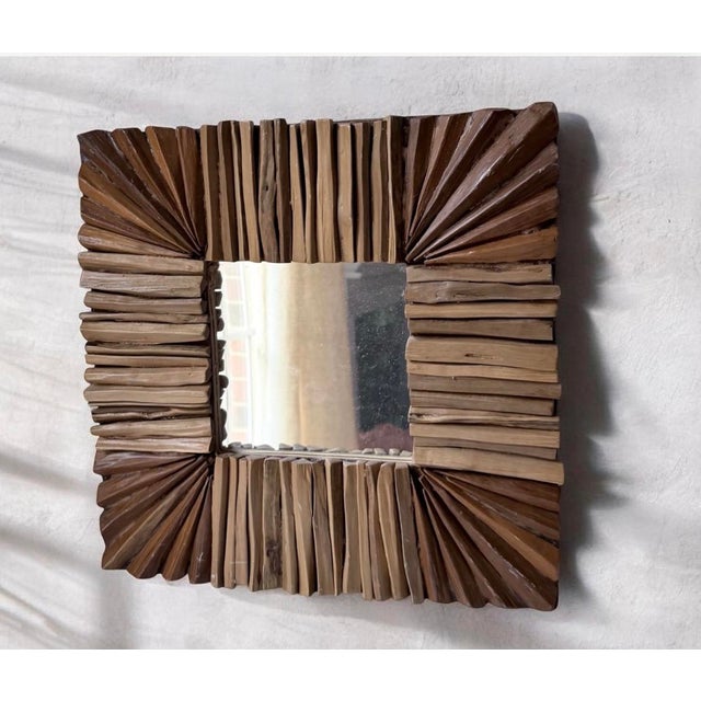 distinctive square wall mirror features a handcrafted frame composed of natural wood and driftwood pieces arranged in a...