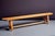 A long solid-wood bench originating from a french monastery, featuring a plank seat on trestle supports with a single...
