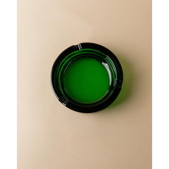 This vintage green glass ashtray from the 1970s embodies a bold yet minimal Mid Century aesthetic. Its clean lines and...