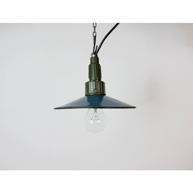Industrial blue enamel pendant light made in Poland during the 1960s. White enamel inside the shade. Green cast aluminium...