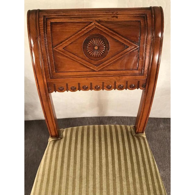 Set of four Neoclassical Chairs, France 19th century The slightly bent backrests are decorated with a rosette and...