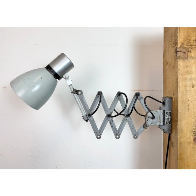 This vintage Industrial adjustable scissor wall lamp was produced in former Czechoslovakia during the 1960s. The lamp has...