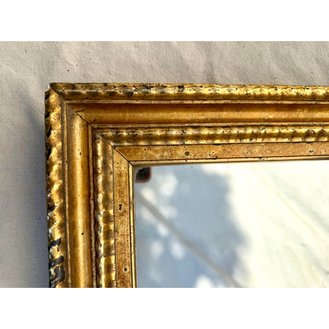 This is a beautiful antique giltwood wall mirror featuring a classic stepped and molded frame profile with layered...