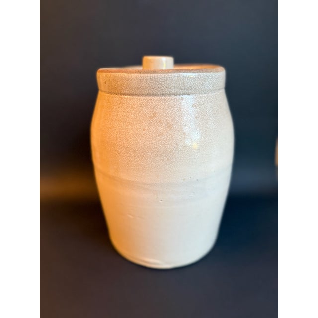 Antique Salt Glazed Stoneware Crock, cream to beige coloration, with lid decorated with tomato red knob. This heavy crock...