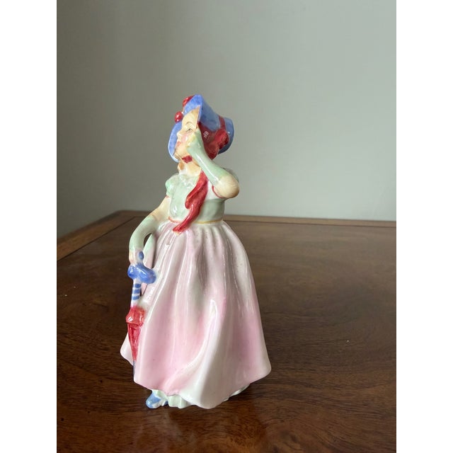 A sweet Royal Doulton porcelain child figurine titled “Babie,” depicting a child in soft pastel attire. The figure is...