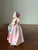 A sweet Royal Doulton porcelain child figurine titled “Babie,” depicting a child in soft pastel attire. The figure is...
