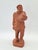 A unique terracotta figure depicting a porter or laborer carrying a large bundle, created in the tradition of 19th-century...