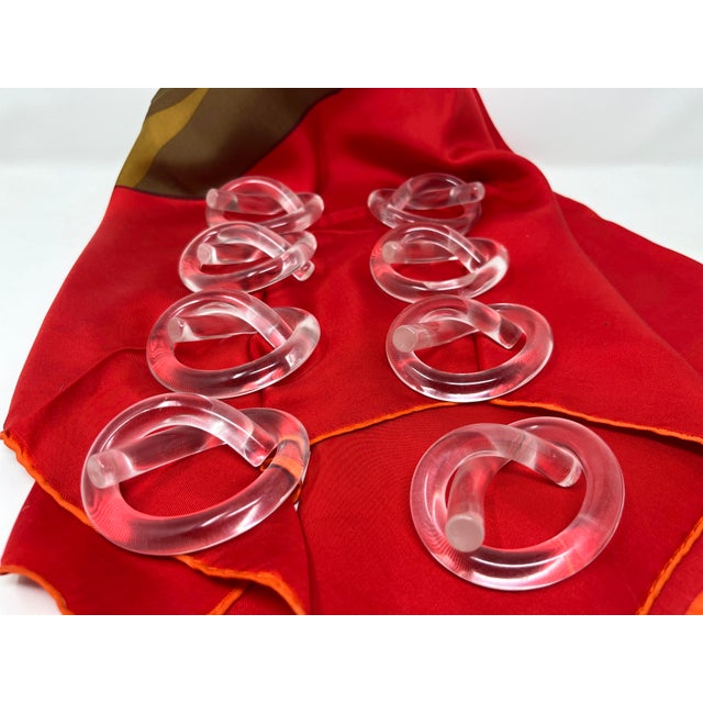 Set of 8 mid-century modern Lucite pretzel-shaped napkin rings designed by Dorothy Thorpe. Single tubes of solid Lucite...