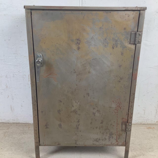 A striking example of rugged utilitarian design, this vintage industrial metal storage cabinet brings a bold factory...