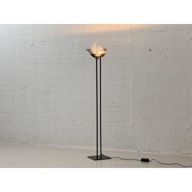 A striking italian floor lamp from the postmodern era of the 1980s, crafted from black lacquered metal with a sculptural...