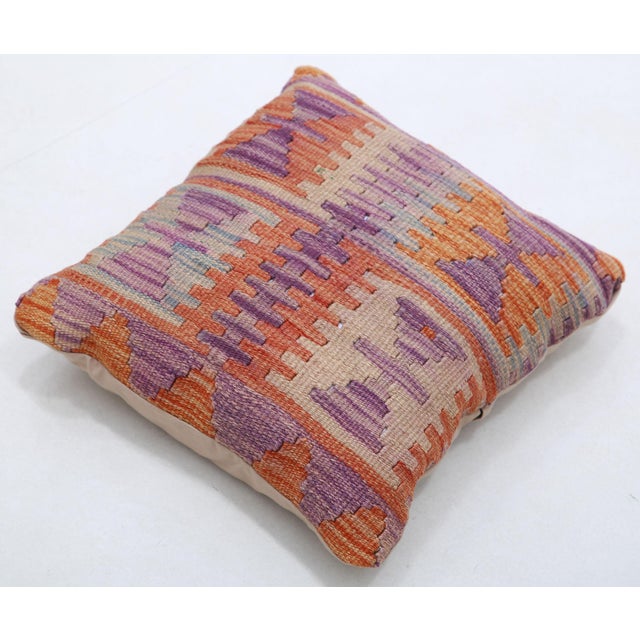 A one-of-a-kind handwoven Afghan wool kilim accent pillow featuring comb-and-triangle tribal motifs in purple and burnt...