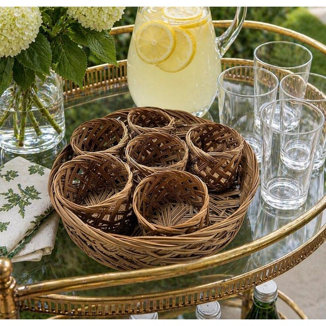 A vintage woven rattan drink-serving set featuring six individual glass holders with integrated coaster bases and a...