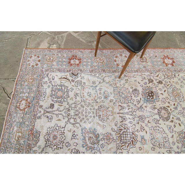 An ethereally large vintage rug with floral arrangements all throughout. Featuring colors of blue, brownish/orange, and...