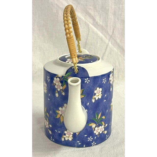 Sweet vintage ceramic teapot with lid. It's made of white porcelain and painted periwinkle blue with pink cherry blossoms....