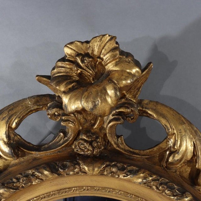 An antique Louis XIV style wall mirror, crafted from carved gilt wood, dating to approximately 1880. Its frame is carved...