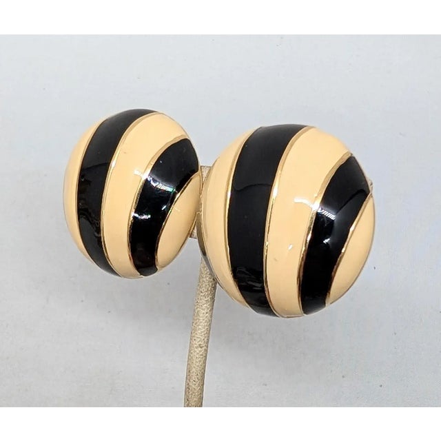 1980s round domed goldtone black and ivory enamel striped clip earrings. Marked "CINER®" on the clips and "CINER©" on the...