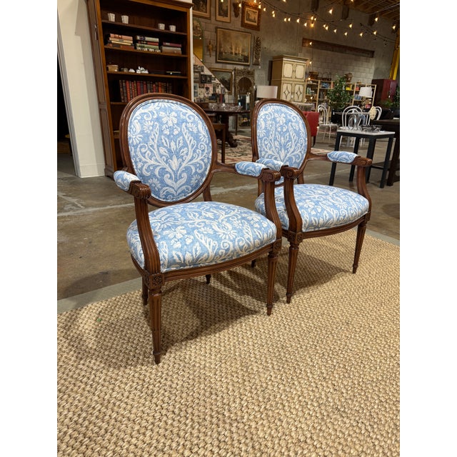 Handsome matched pair of Louis XVI style fauteuils — the classic French neoclassical open-arm chair, with finely carved...