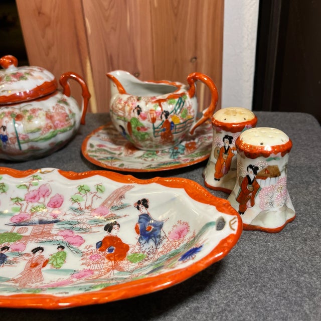 Intricate hand painted details of people and garden scenes. White plates with a rich burnt orange color. (1) Elongated...