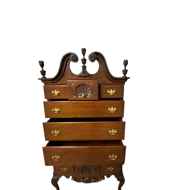 Elegant Queen Anne style highboy featuring a graceful bonnet top, carved shell motifs, brass hardware, and cabriole legs...