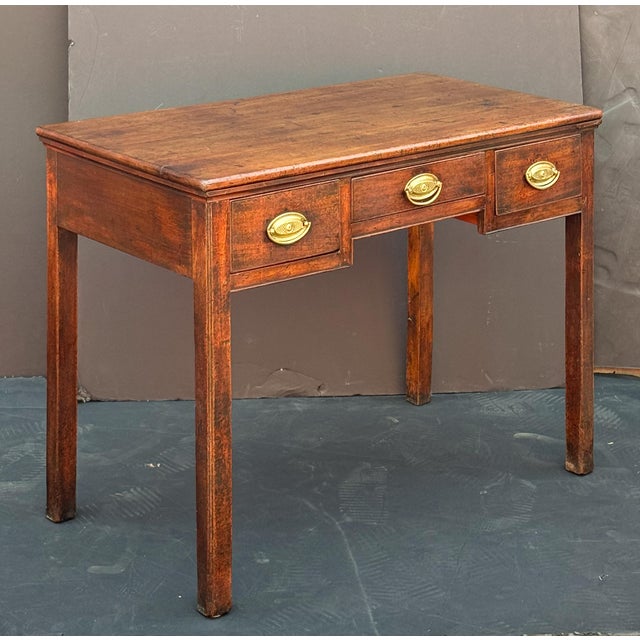 A fine English side table or writing desk from the late Georgian Period, featuring a moulded rectangular top over a frieze...