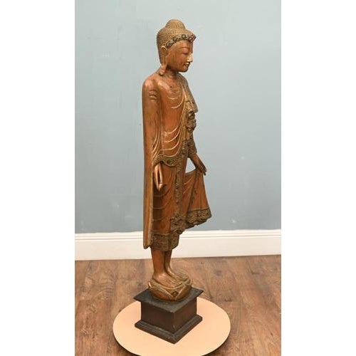A finely carved Burmese (Myanmar) wooden figure of a standing Buddha, richly decorated and presented on a later plinth...