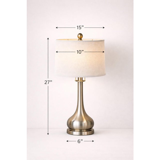 A striking matched pair of sculptural vintage table lamps with elegant nickel-toned bodies and crisp tailored linen...